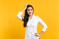 Portrait of preoccupied worried young woman in white shirt looking camera putting hand on head isolated on bright yellow Royalty Free Stock Photo