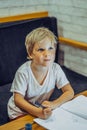 Portrait Preschool boy dreamy airy fairy look up thoughtful, hold pen notebook, think idea to draw write, facial