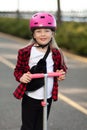 Portrait of a preschool child girl in a helmet on a scooter
