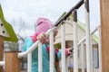 Portrait of a preschool child on the playground. A five-year-old girl in a pink hat walks up and down the stairs holding onto the Royalty Free Stock Photo