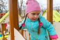 Portrait of a preschool child on the playground. A five-year-old girl in a pink hat walks up and down the stairs holding onto the Royalty Free Stock Photo