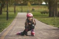 Portrait of a preschool girl on roller skates, sitting on her knee waiting for the start. Riding in the park