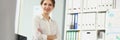 Presentable employee girl posing sitting on desk in office, stylish look for work