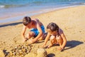 Portrait of preteen boy brother, little girl family sitting on beach seashore, playing with sand, building castles. Royalty Free Stock Photo