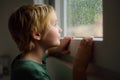 Portrait of preteen boy standing at the window. Child watching the rain outside Royalty Free Stock Photo