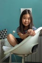 Portrait of adorable little asian girl child sitting in lotus position on chair in nursery at home