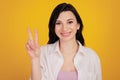 Portrait of pretty adorable positive girl show v-sign on yellow background