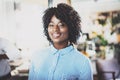 Portrait of pretty african american business woman with afro looking and smiling at the camera.Interior on background in Royalty Free Stock Photo