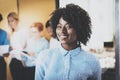 Portrait of pretty african american business woman with afro smiling at the camera.Coworking team on background in Royalty Free Stock Photo