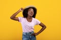 Portrait of pretty african american lady in casual clothes and straw hat on yelow studio background Royalty Free Stock Photo
