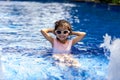 Portrait of pretty asian child smilling and posing on swimming pool background wearing pink swim suit and sun glasses Royalty Free Stock Photo