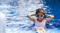Portrait of pretty asian child smilling and posing on swimming pool background wearing pink swim suit and sun glasses Royalty Free Stock Photo