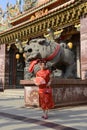 Portrait pretty Asian female in red traditional Chinese costume holding a fan standing and posing at stone lion. Royalty Free Stock Photo
