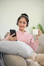 Pretty Asian girl chilling in her living room, listening to music through headphones Royalty Free Stock Photo