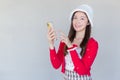 Portrait of a pretty Asian teen girl wearing a red dress and white hat happily smile using a smartphone on a white background Royalty Free Stock Photo