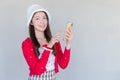 Portrait of a pretty Asian teen girl wearing a red dress and white hat happily smile using a smartphone on a white background Royalty Free Stock Photo