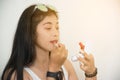 Portrait of pretty Asian woman applies red lipstick . Hand of make-up master, painting lips of young beauty model female. Royalty Free Stock Photo