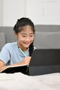 Portrait of a pretty Asian young preteen girl using tablet to study online lesson Royalty Free Stock Photo