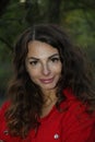 Portrait of a pretty, attractive woman in a red overall leaning against a tree trunk Royalty Free Stock Photo