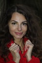 Portrait of a pretty, attractive woman in a red overall leaning against a tree trunk Royalty Free Stock Photo