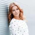 Portrait of a pretty attractive young woman with blond curly hair with blue eyes in a fashionable sweater near the metal wall Royalty Free Stock Photo