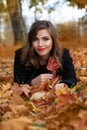 Portrait of pretty autumn brunette woman smiling. Cheerful lady on a golden autumn leaves background Royalty Free Stock Photo