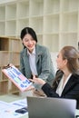 Asian female office worker or assistant showing financial data on the report to her boss Royalty Free Stock Photo