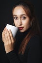 Portrait of pretty beautiful young woman wearing black sweater isolate over dark background. Holding white cup mug. Coffee or tea Royalty Free Stock Photo