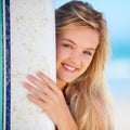 The ideal surfer girl. Portrait of a pretty blonde with her surfboard on the beach.