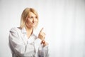 Portrait of a pretty blonde smiling woman posing on a white background and pointing somewhere. Happy girl model in white Royalty Free Stock Photo