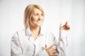 Portrait of a pretty blonde smiling woman posing on a white background and pointing somewhere. Happy girl model in white Royalty Free Stock Photo