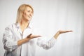 Portrait of a pretty blonde smiling woman posing on a white background and pointing somewhere. Happy girl model in white Royalty Free Stock Photo