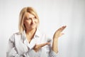 Portrait of a pretty blonde smiling woman posing on a white background and pointing somewhere. Happy girl model in white Royalty Free Stock Photo