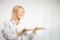 Portrait of a pretty blonde smiling woman posing on a white background and pointing somewhere. Happy girl model in white Royalty Free Stock Photo