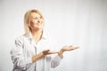 Portrait of a pretty blonde smiling woman posing on a white background and pointing somewhere. Happy girl model in white Royalty Free Stock Photo