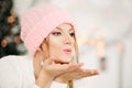 Lovely girl in pink woolen beanie hat making air kiss with hands. Royalty Free Stock Photo