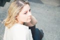 Portrait of a pretty blue eyed blonde girl sitting on the steps in a pensive expression Royalty Free Stock Photo