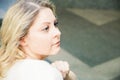 Portrait of a pretty blue eyed blonde girl sitting on the steps in a pensive expression Royalty Free Stock Photo