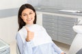 Brunette female patient smiling and showing thumb up in dentistry Royalty Free Stock Photo