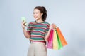 Portrait of a pretty casual girl holding shopping bags while using mobile phone isolated over white background Royalty Free Stock Photo