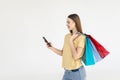 Portrait of a pretty woman holding shopping bags while using mobile phone isolated over white background Royalty Free Stock Photo