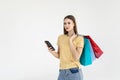 Portrait of a pretty woman holding shopping bags while using mobile phone isolated over white background Royalty Free Stock Photo