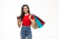 Portrait of a pretty woman holding shopping bags while using mobile phone isolated over white background Royalty Free Stock Photo