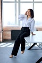 Portrait Of Pretty Caucasian Brunette Female In Formal Clothes Sitting On Office Desk Table