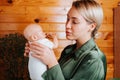 Portrait of pretty caucasian young woman holding newborn baby doll in arms and looking at her while standing indoors. Royalty Free Stock Photo