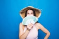 Portrait of pretty charming woman covering closing half face with fan from dollars looking out with eyes at camera isolated on blu Royalty Free Stock Photo