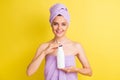 Portrait of pretty cheerful naked girl holding in hand shampoo bottle product isolated over vibrant yellow color