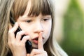 Portrait of pretty child girl with long hair holding her finger lo lips in hush gesture talking on cell phone. Little female kid Royalty Free Stock Photo