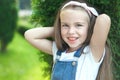 Portrait of pretty child girl standing in summer park looking in camera smiling happily Royalty Free Stock Photo