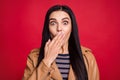 Portrait of pretty confused young woman hand covering mouth lips wear striped jumper isolated on red color background Royalty Free Stock Photo